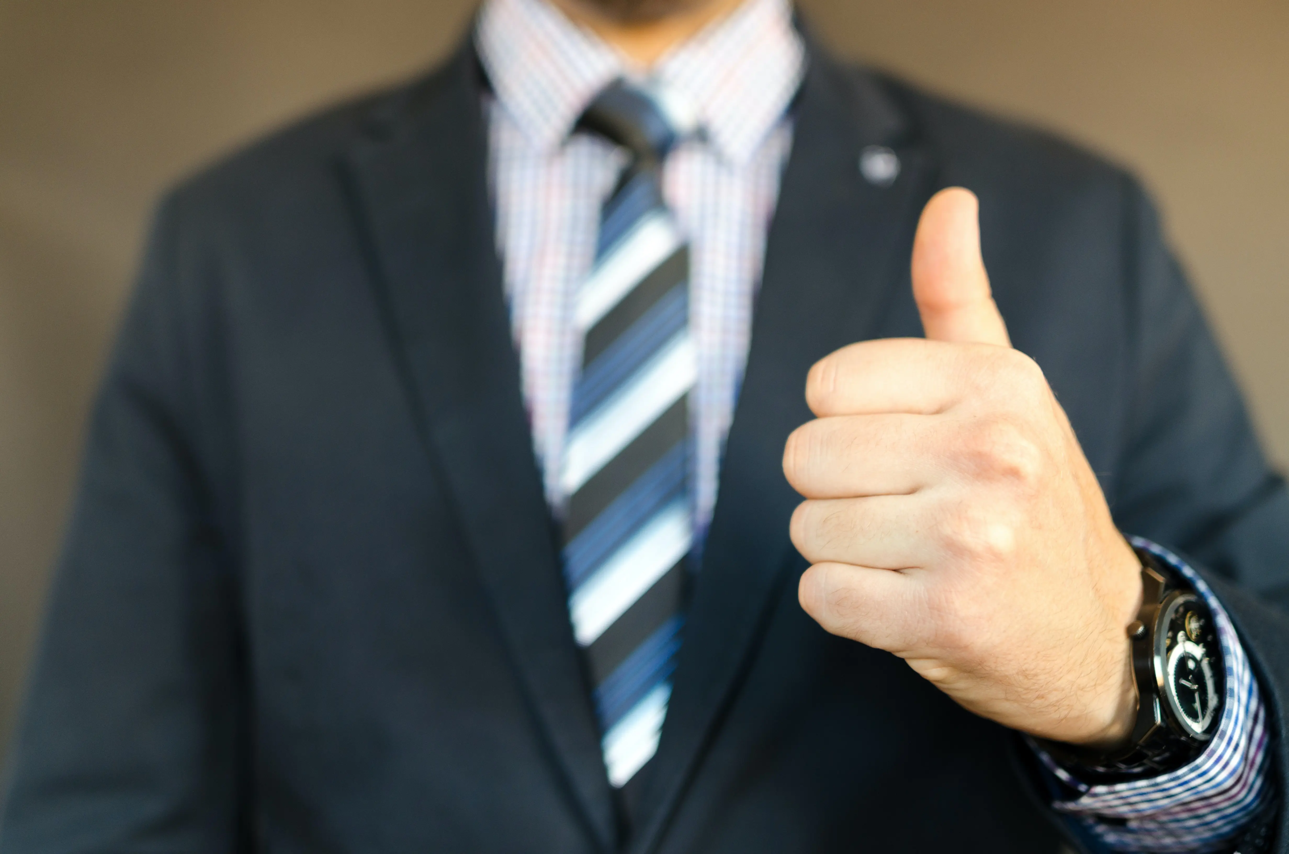 A man in a suit and tie giving the thumbs up.