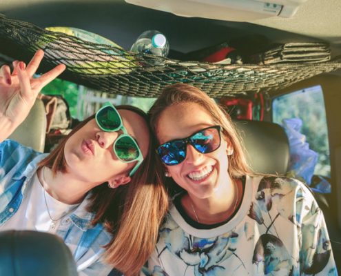 Two friends laughing and having fun inside of car