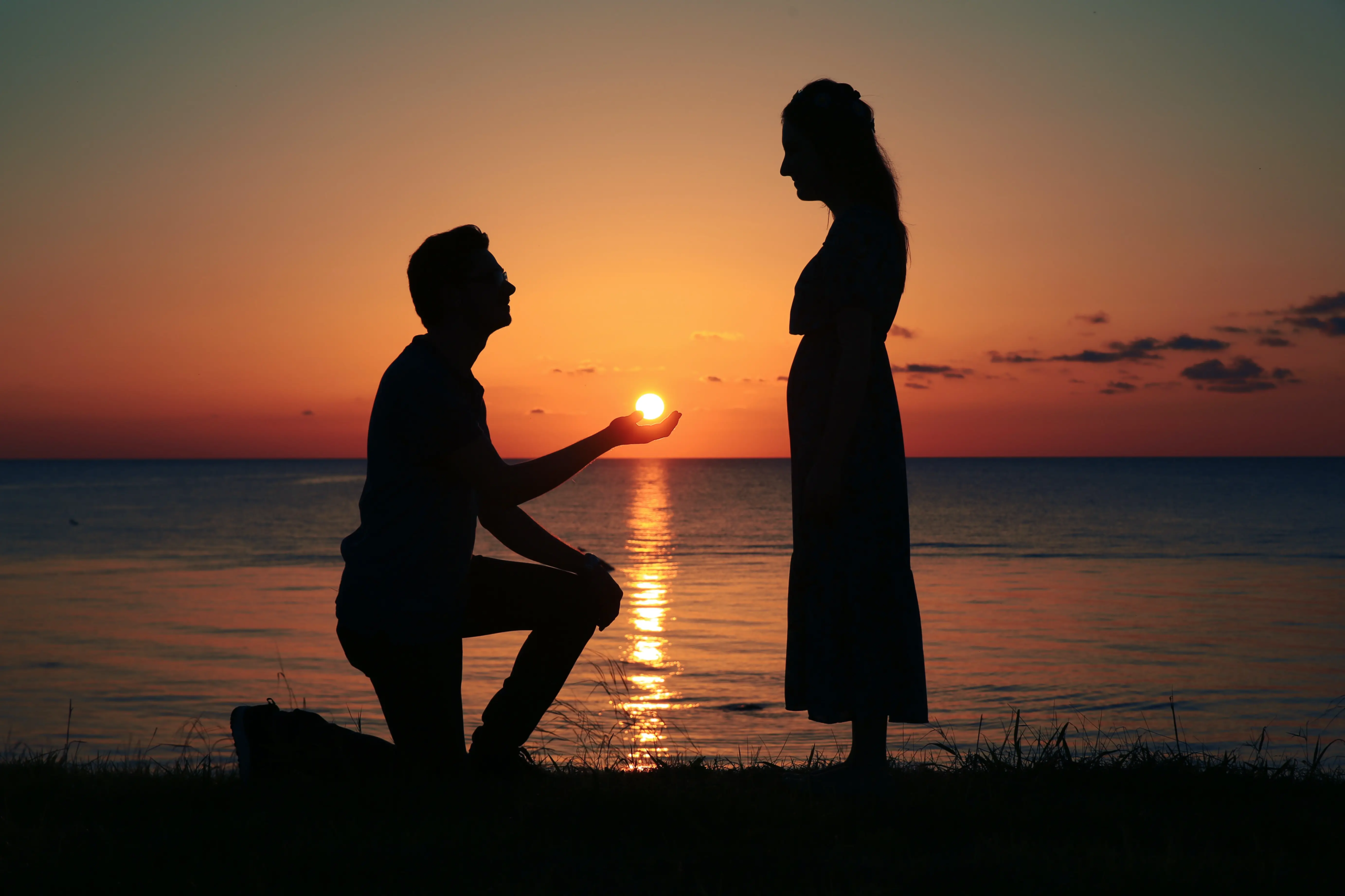 A man is kneeling down to propose to his girlfriend.